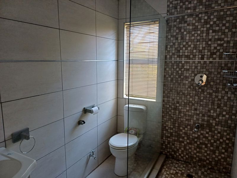 Modern bathroom featuring a walk-in shower with a mosaic tile accent wall, neutral ceramic wall tiles, and a clean, functional layout.