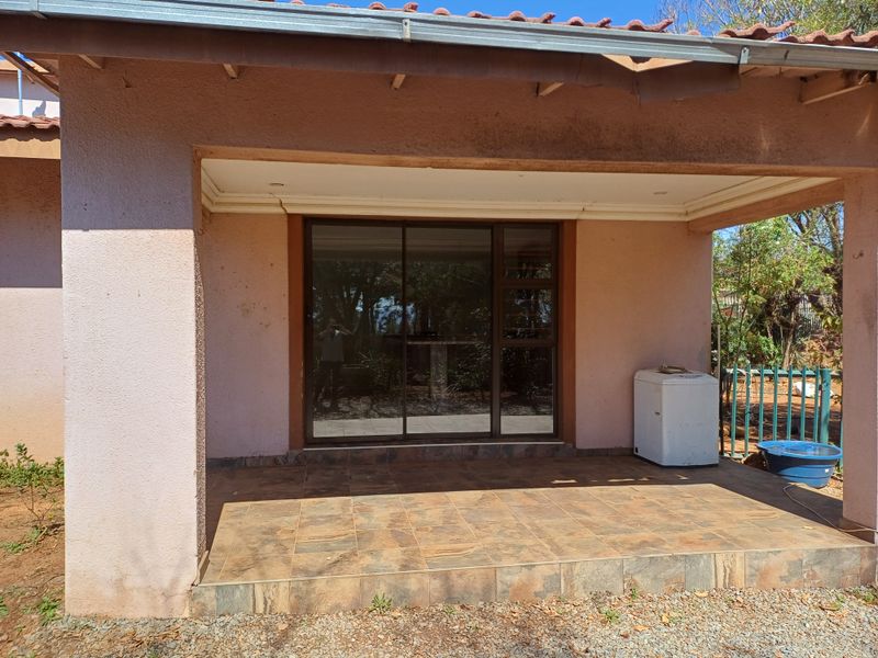 A covered outdoor patio area featuring tiled flooring and a large sliding glass door, providing direct access to the property interior.