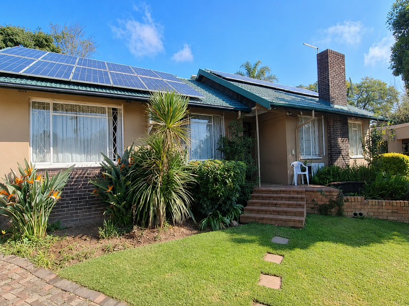 Front elevation of a single-story house featuring a tiled roof with integrated solar panels, a prominent brick chimney, and a landscaped front garden.