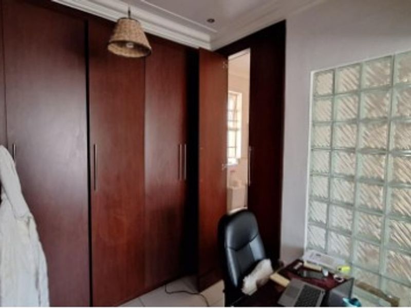 Bedroom featuring extensive dark wood built-in cupboards and a decorative glass block wall, providing ample storage and unique architectural character.