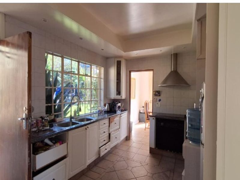 Functional kitchen featuring tiled flooring, stone countertops, built-in cabinetry, and an extractor fan, with direct access to the exterior.