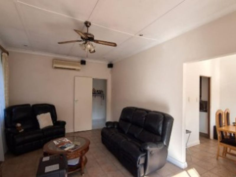Open plan living and dining area featuring tiled flooring, a ceiling fan, and a wall-mounted split system air conditioner.