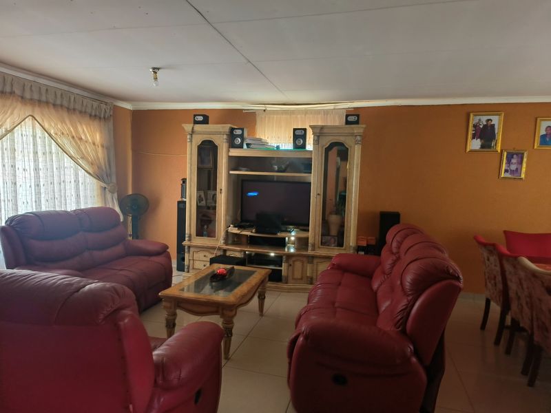 A living room featuring tiled flooring and a built-in entertainment unit, offering a functional space for relaxation and media storage.