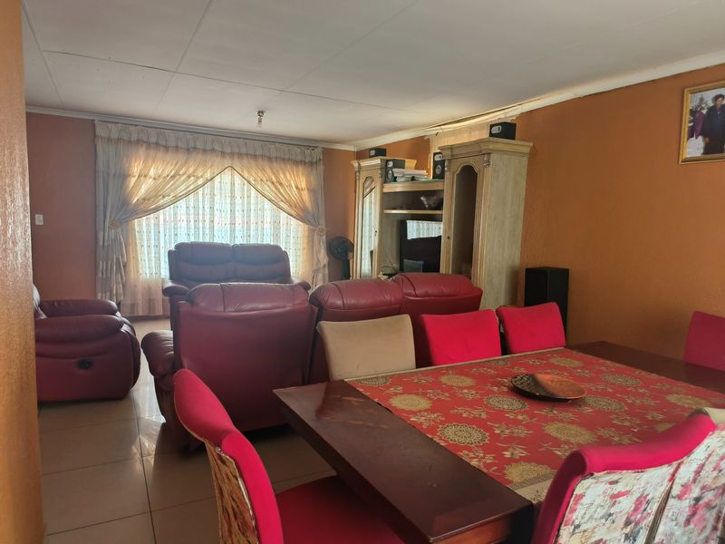 Open plan living and dining area featuring tiled flooring and large window with curtain treatments.
