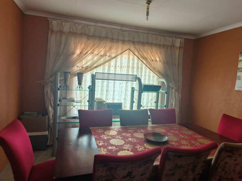 A dining room featuring neutral wall tones and large window treatments, providing a functional space for family meals.