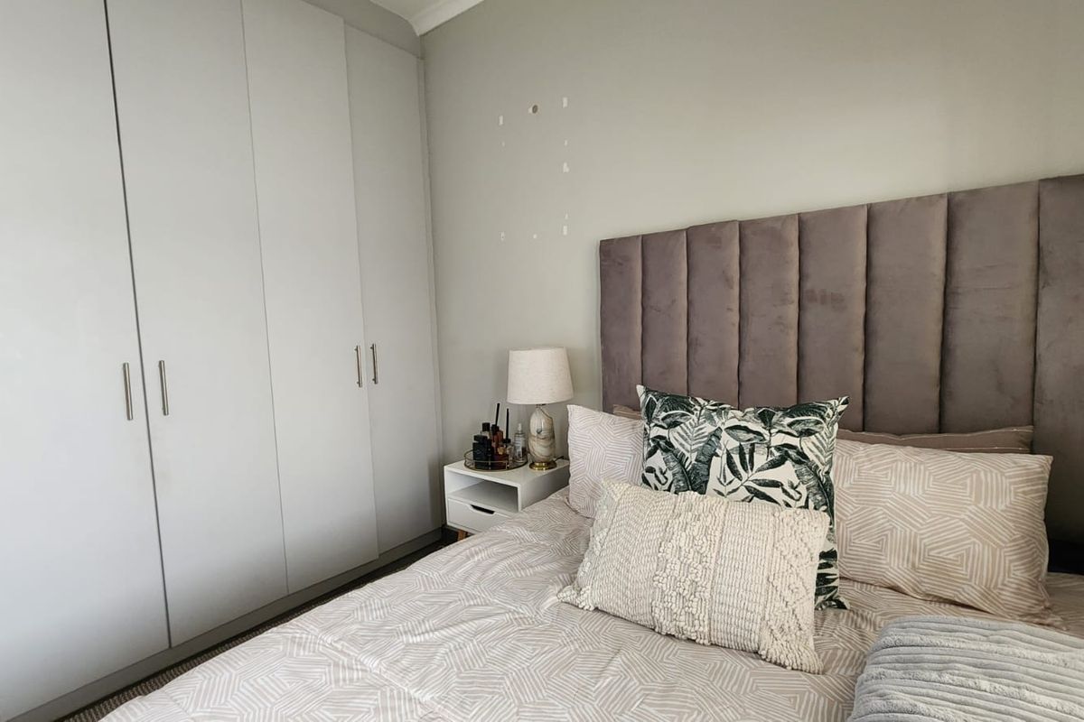 A bedroom featuring floor-to-ceiling built-in cupboards and neutral wall finishes.