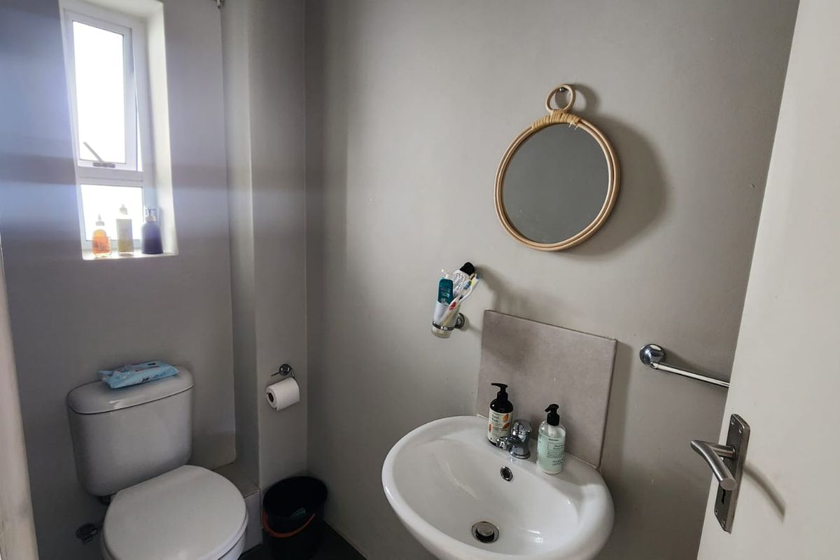 A compact bathroom featuring a standard toilet, pedestal basin, and a small window for natural light.