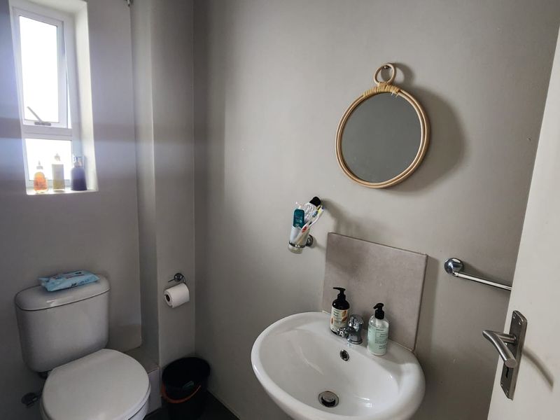 A compact bathroom featuring a standard toilet, pedestal basin, and a small window for natural light.