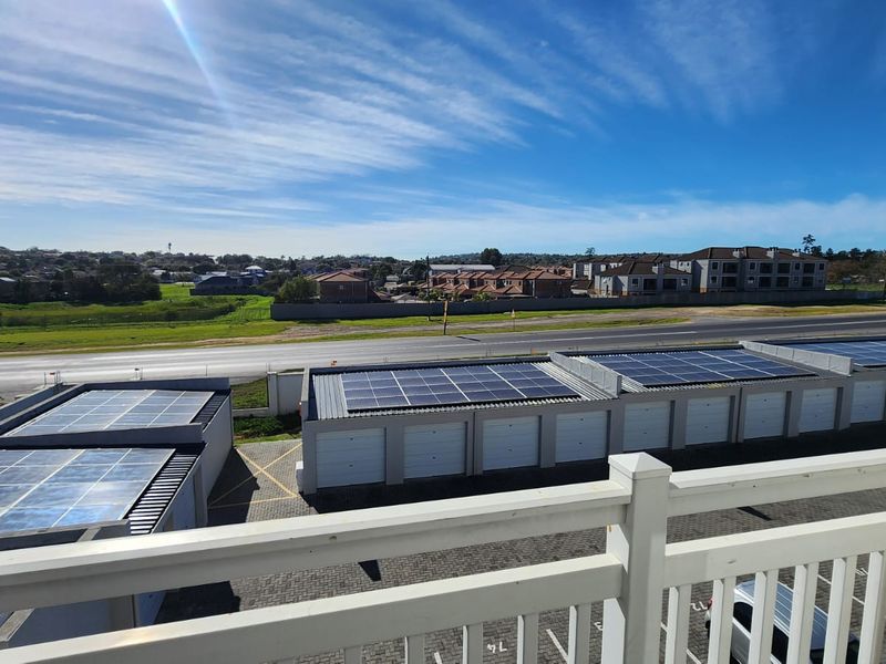 Elevated view from a balcony overlooking a complex with solar-equipped garages and surrounding neighbourhood.