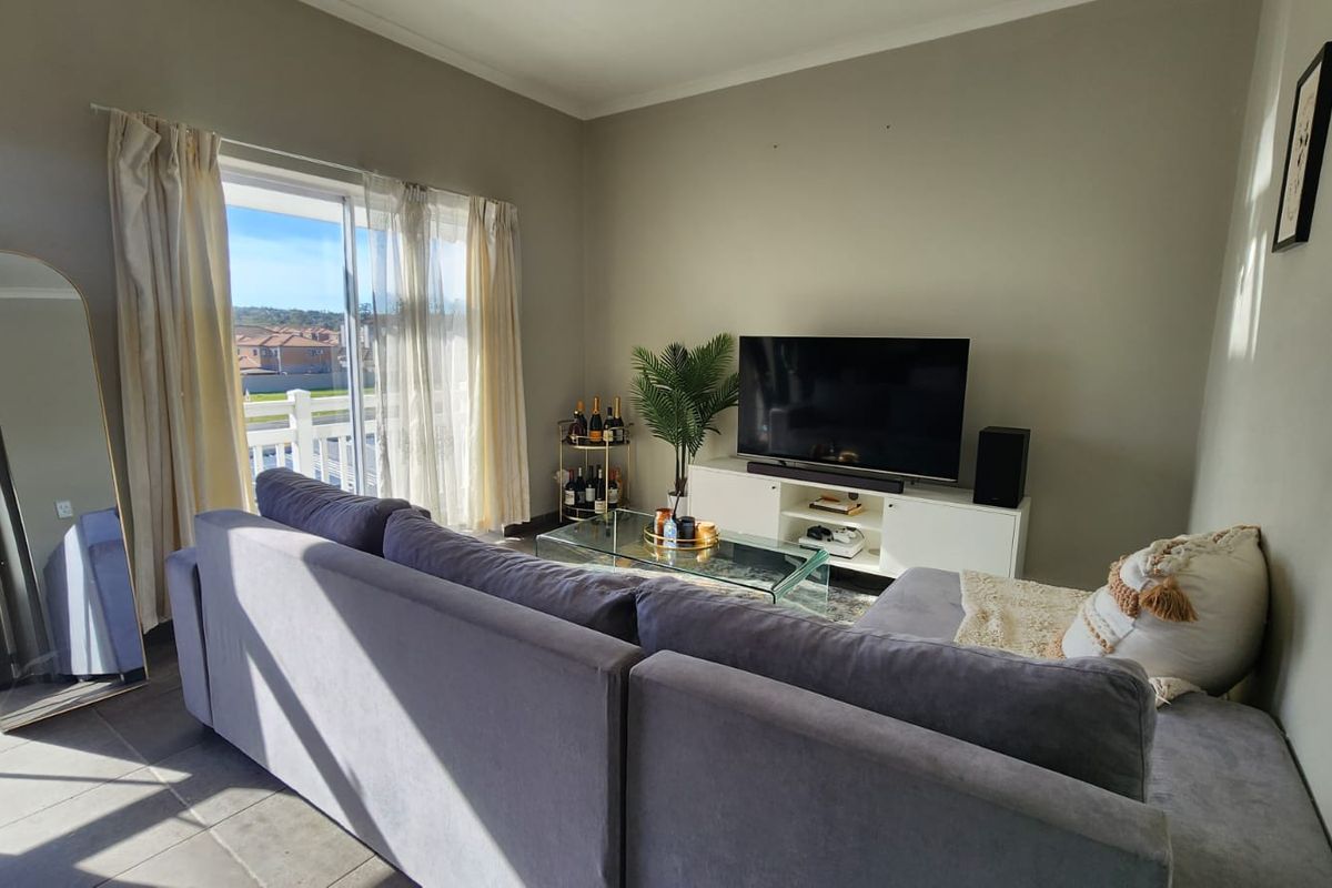A comfortable living room featuring tiled flooring and a large sliding glass door that provides access to an outdoor balcony area.