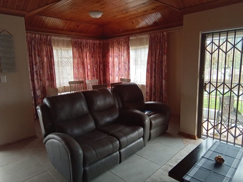 Living room featuring a timber tongue and groove ceiling, tiled flooring, and a security gate providing access to the exterior.