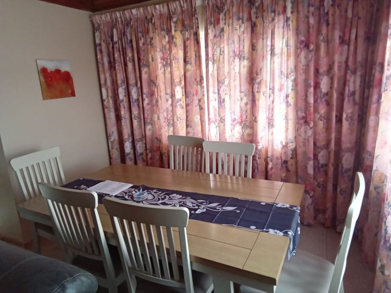 A dining area featuring a timber ceiling trim and floor-to-ceiling floral curtains, providing a traditional aesthetic.