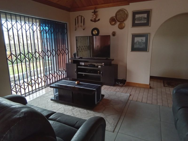 A living room featuring tiled flooring, a timber ceiling, and a sliding door with a security gate leading to the exterior.