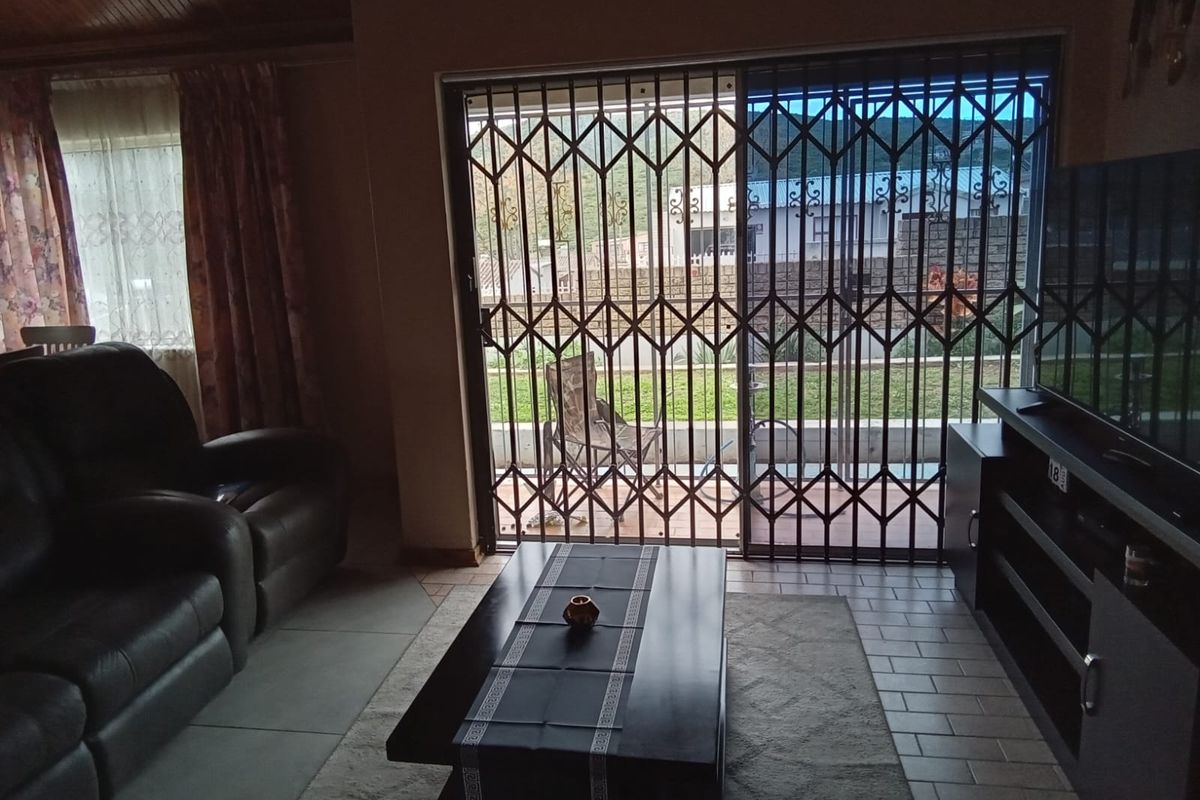 A living room featuring tiled flooring, a timber ceiling, and a sliding glass door with a security gate leading to the outdoor area.