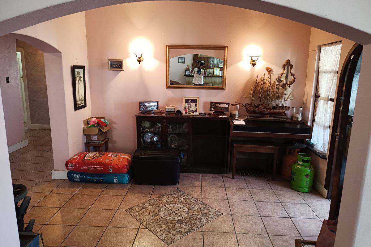 A living area featuring tiled flooring, a decorative archway, and wall-mounted lighting fixtures.