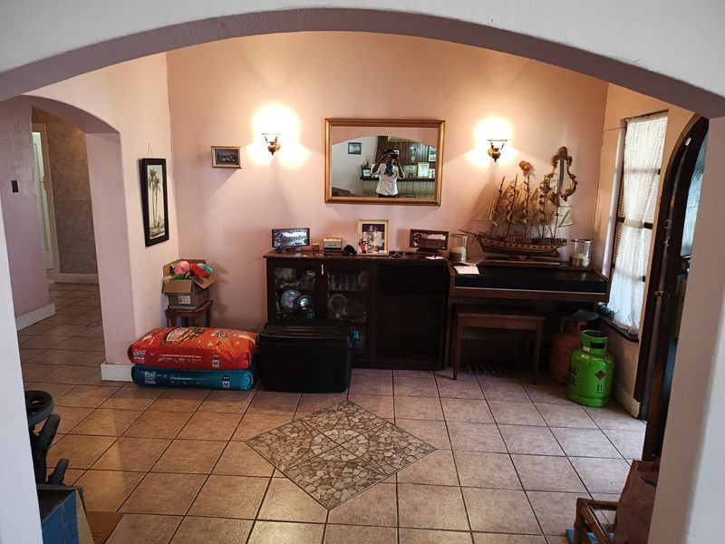 A living area featuring tiled flooring, a decorative archway, and wall-mounted lighting fixtures.