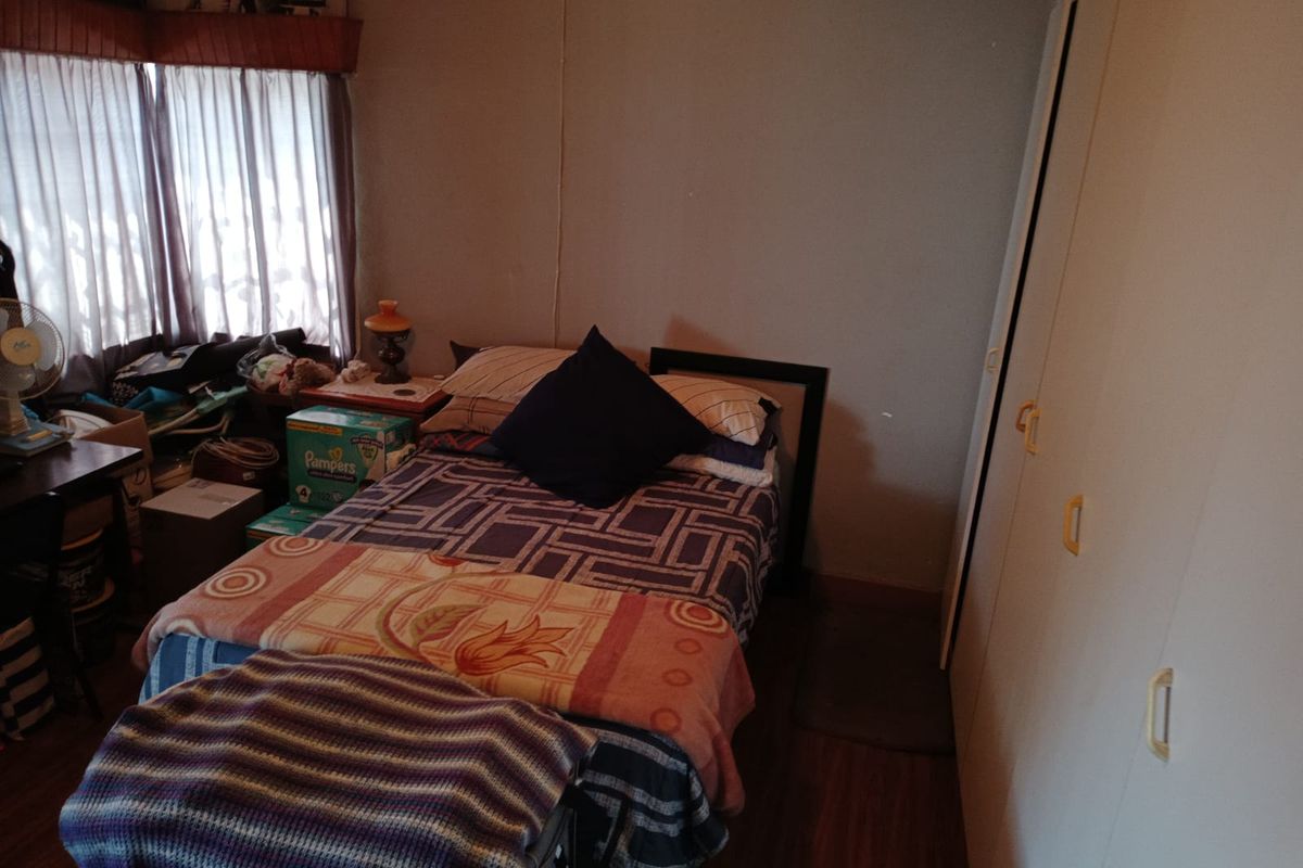 A functional bedroom featuring built-in cupboards and laminate flooring, providing a practical space for rest and storage.