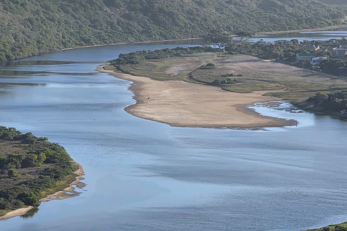 An aerial view of a scenic estuary featuring a sandbank and surrounding natural coastal landscape.