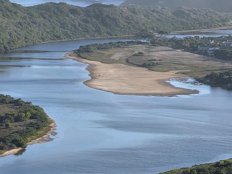 An aerial view of a scenic estuary featuring a sandbank and surrounding natural coastal landscape.