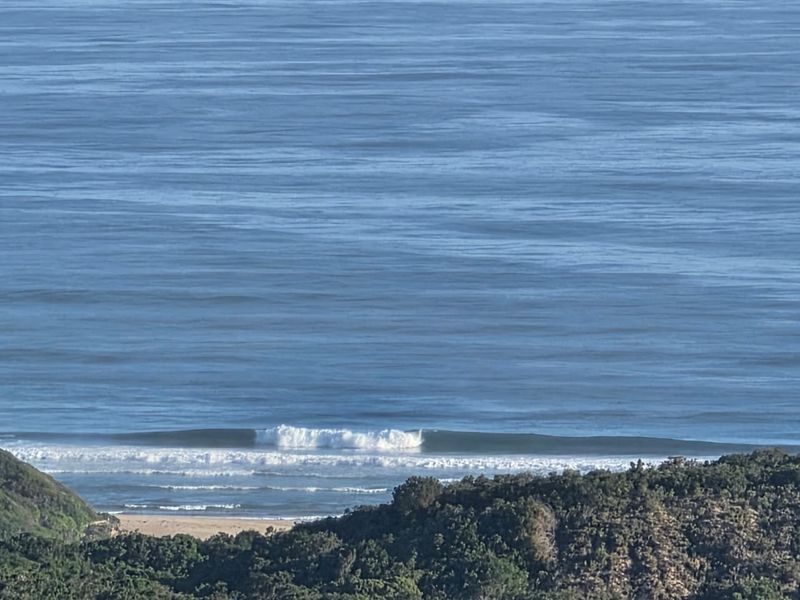 A scenic elevated view of the ocean and coastline, showcasing the natural landscape and surf conditions.