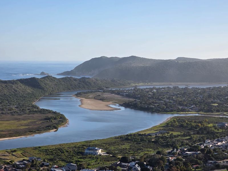 A scenic aerial view of the coastal landscape, featuring a river estuary, surrounding hills, and residential development.
