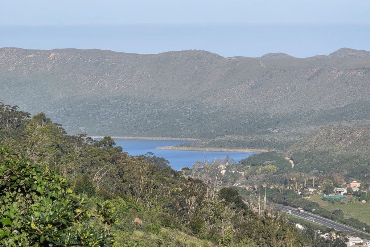 A scenic elevated view overlooking a lake, surrounding hills, and natural landscape.