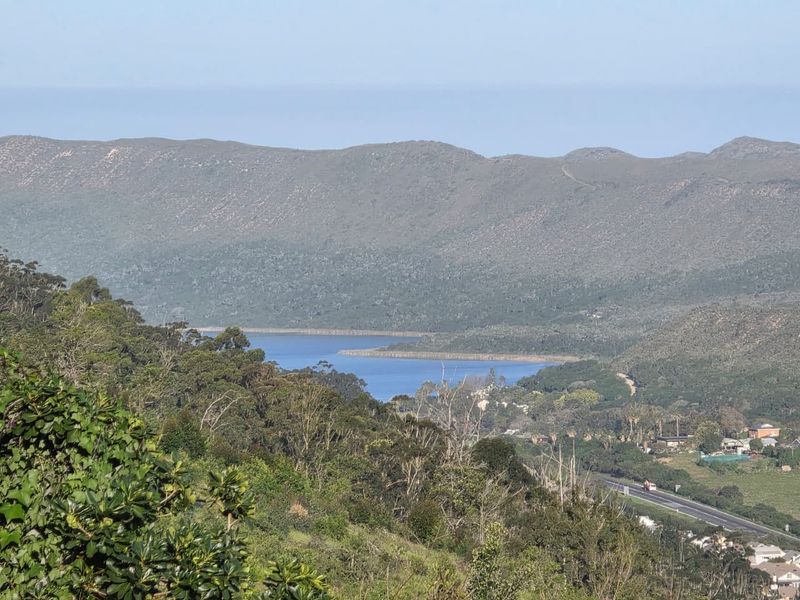 A scenic elevated view overlooking a lake, surrounding hills, and natural landscape.