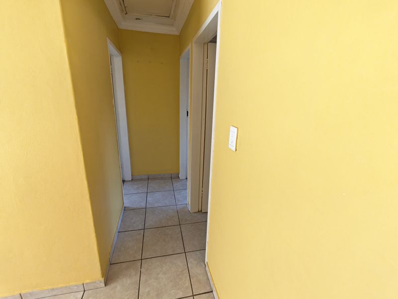 A functional hallway featuring tiled flooring and access to multiple rooms, finished with bright yellow wall paint.