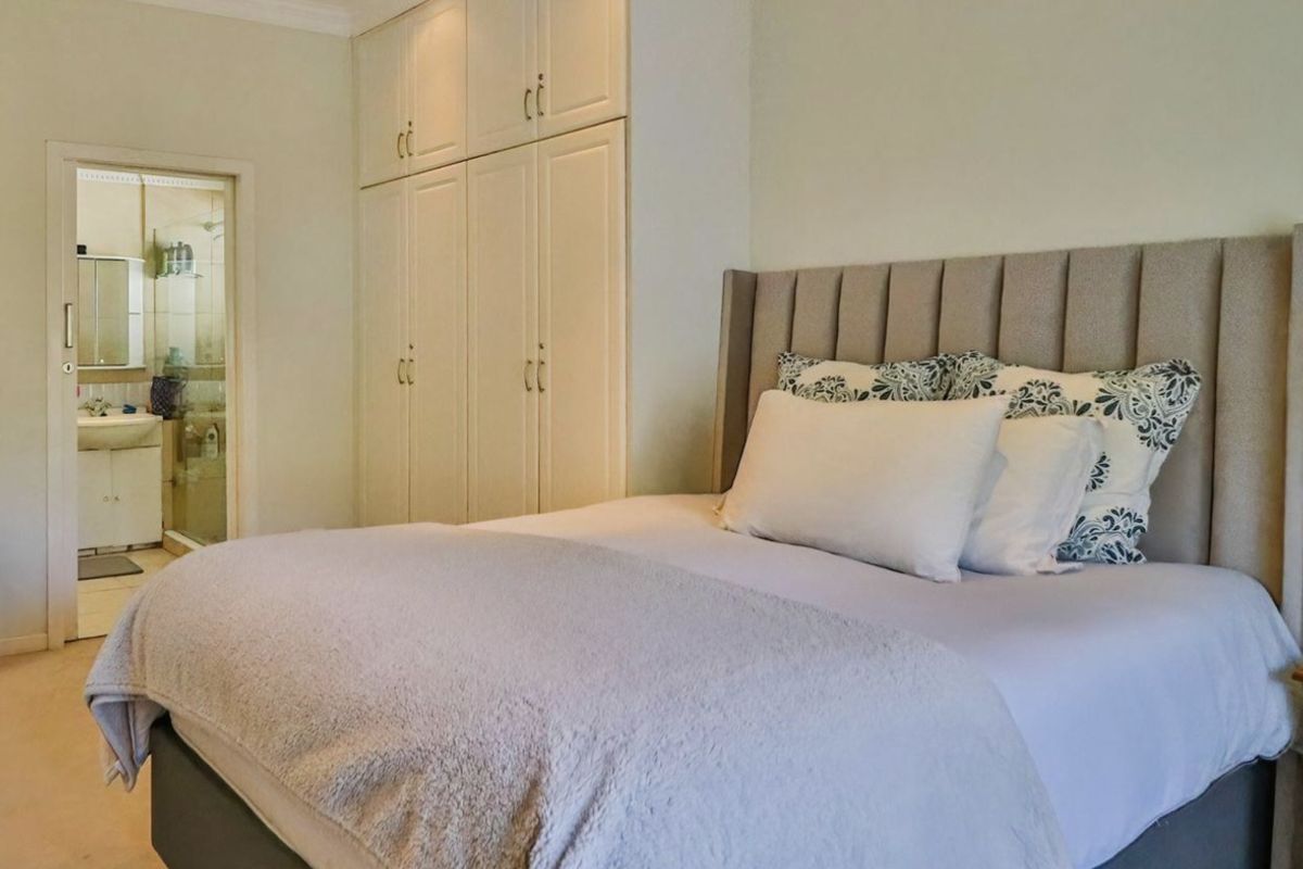 A well-maintained bedroom featuring built-in cupboards, recessed lighting, and direct access to an en-suite bathroom.