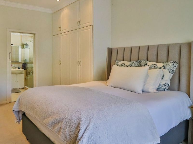 A well-maintained bedroom featuring built-in cupboards, recessed lighting, and direct access to an en-suite bathroom.