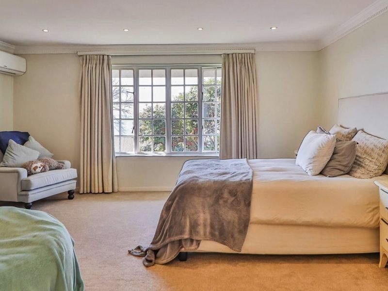Spacious bedroom featuring neutral carpeting, recessed downlighting, decorative cornicing, and a large multi-pane window providing natural light.