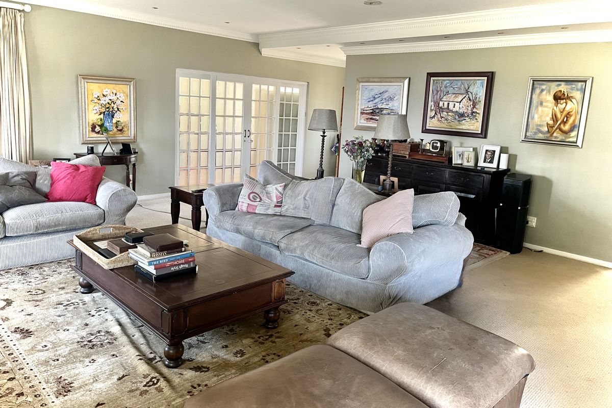 Spacious living room featuring crown molding, recessed lighting, and classic french doors leading to an adjacent area, finished with neutral carpeting.