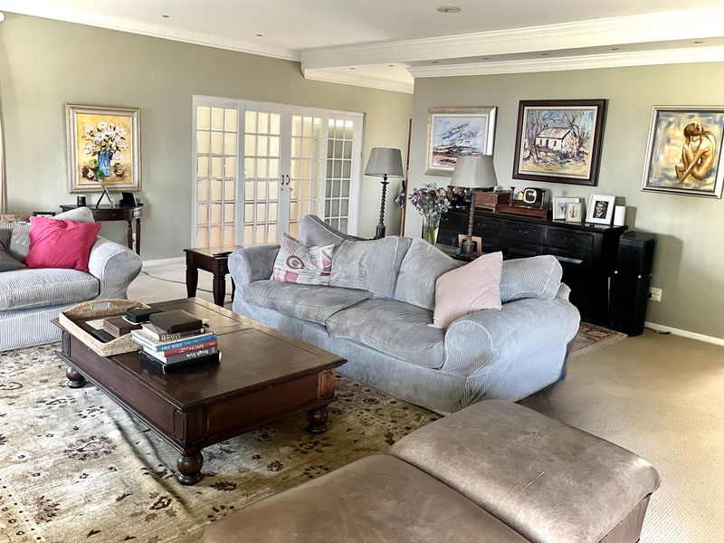 Spacious living room featuring crown molding, recessed lighting, and classic french doors leading to an adjacent area, finished with neutral carpeting.