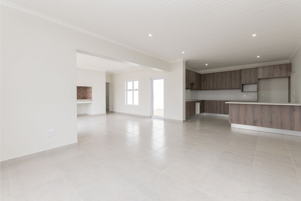 Spacious open-plan living area featuring a modern kitchen with built-in cabinetry, a breakfast island, tiled floors, and a built-in fireplace.