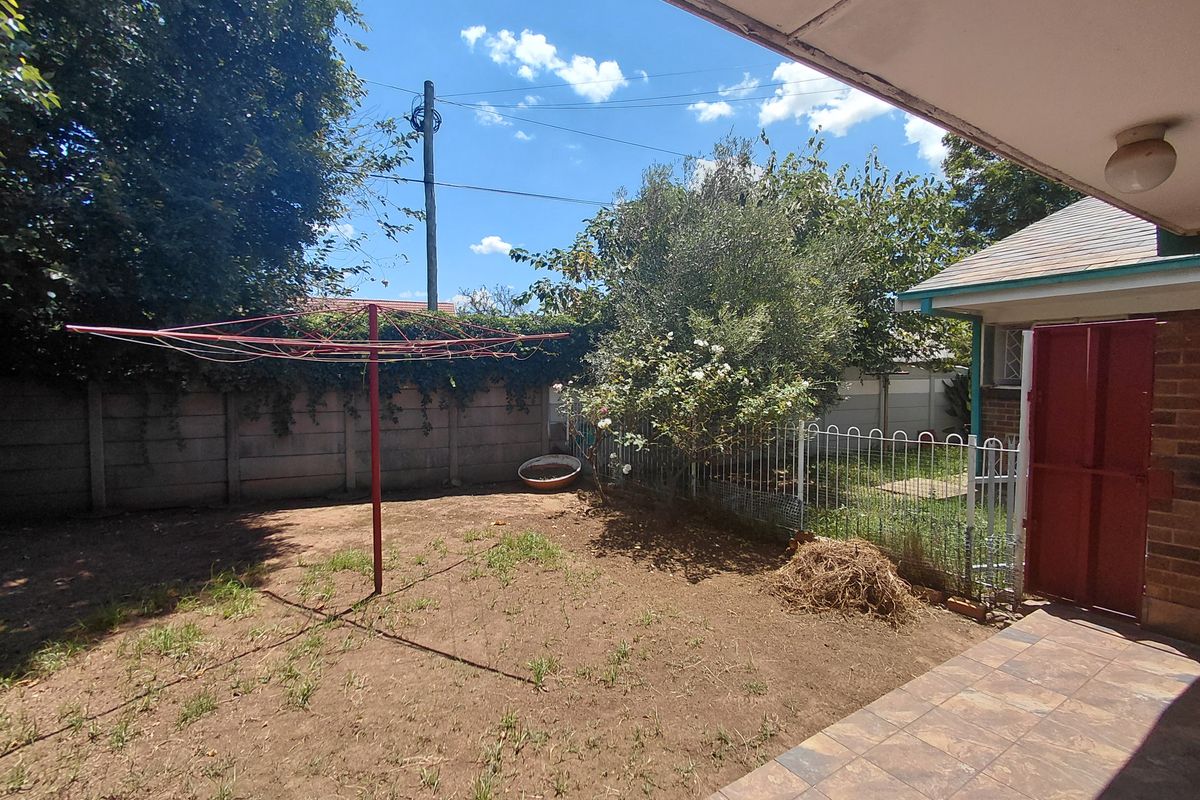 Rear garden area featuring a tiled patio, precast boundary wall, and a rotary clothesline, offering potential for landscaping and outdoor improvement.
