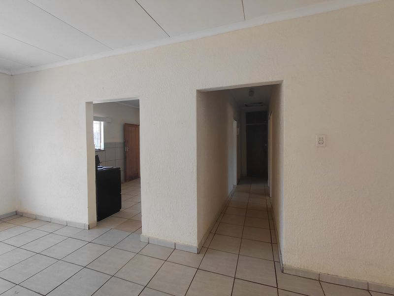 An empty hallway with tiled flooring and textured walls, providing access to adjacent rooms within the townhouse.