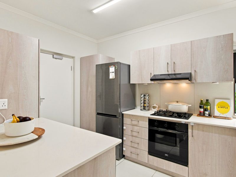 Modern kitchen featuring light wood-grain cabinetry, stone countertops, integrated gas cooktop, built-in oven, and an extractor fan.