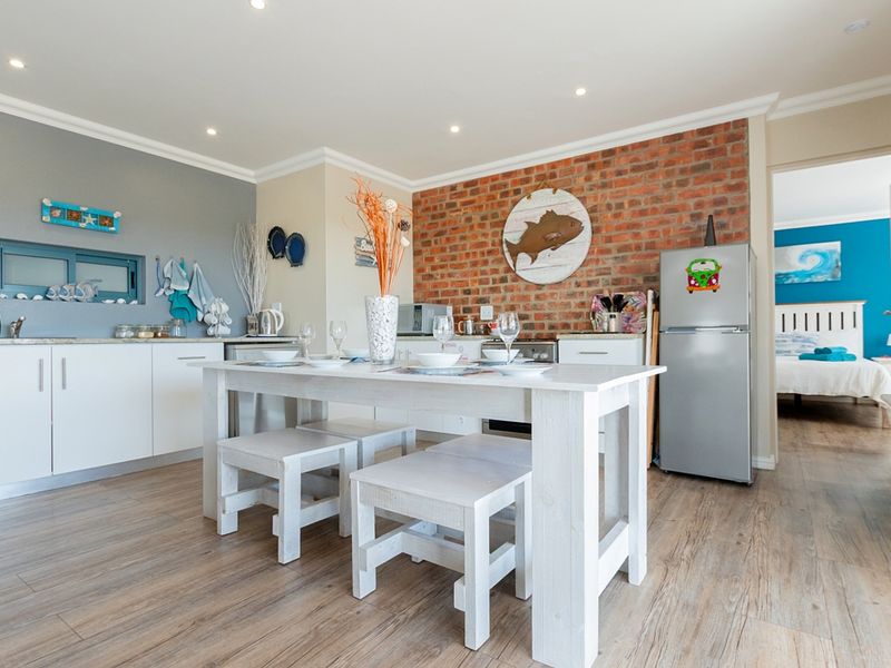 Open-plan kitchen and dining area featuring exposed brick accents, modern laminate flooring, and recessed lighting, creating a bright and functional living space.