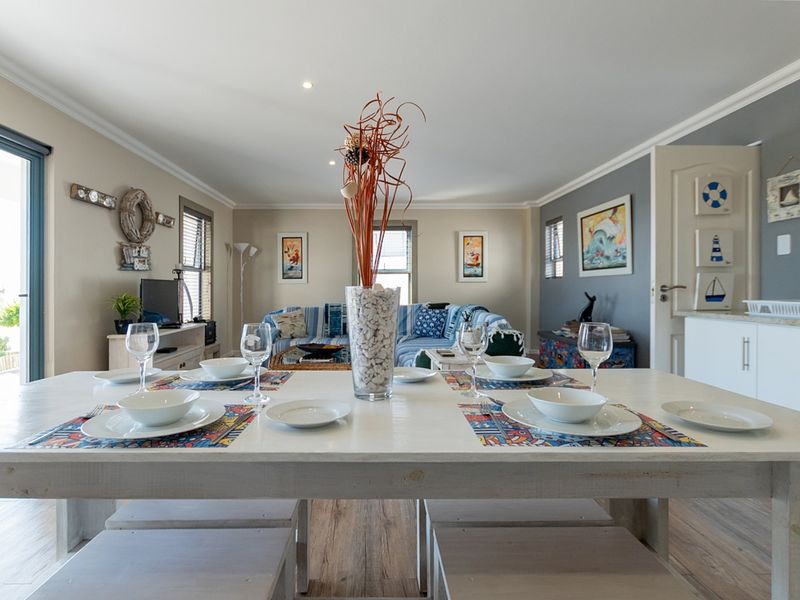 An open-plan living and dining area featuring laminate flooring, recessed lighting, and a sliding glass door providing access to the exterior.