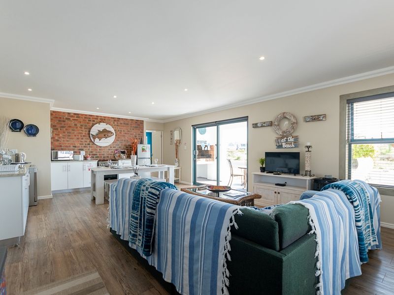 Spacious open-plan living area featuring an exposed brick wall, modern kitchen cabinetry, and seamless access to the outdoor patio through sliding glass doors.