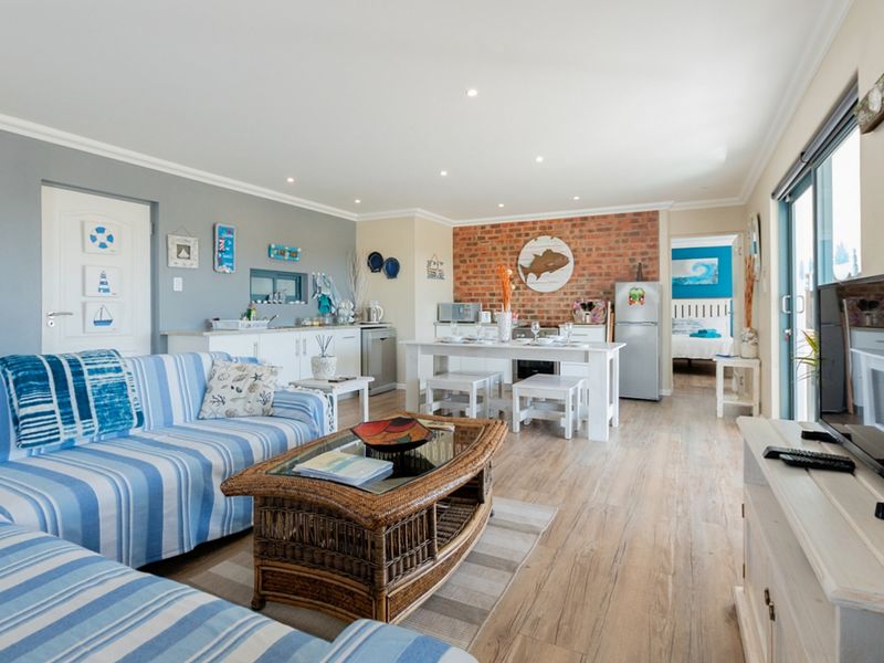 Spacious open-plan living and dining area featuring a distinctive exposed brick wall, modern laminate flooring, and seamless access to the outdoor space.