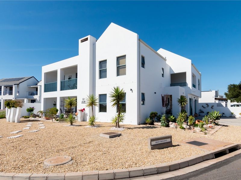 A well-maintained double-storey residential property featuring a clean white facade, multiple balconies, and landscaped gravel garden area.