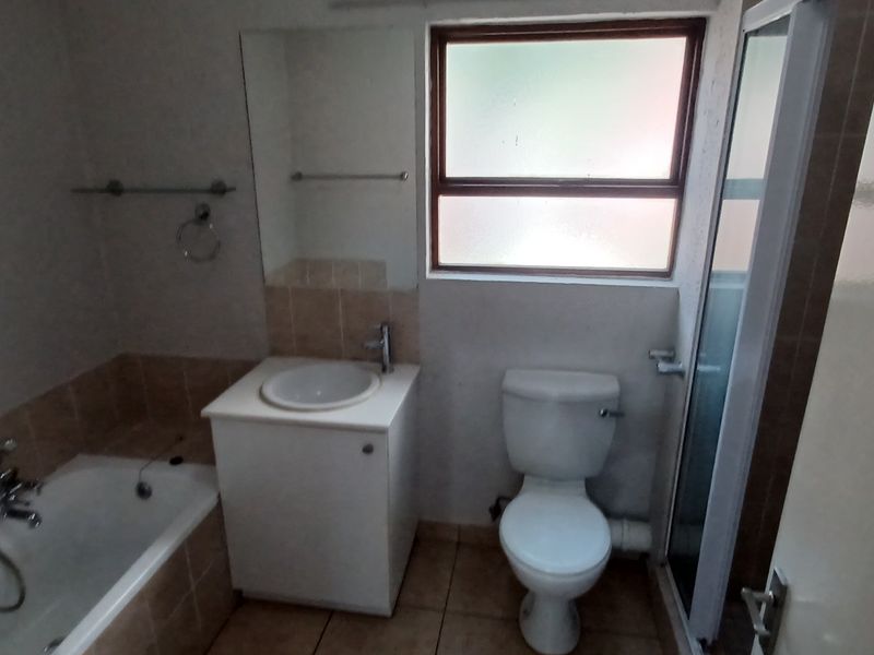 A functional bathroom featuring a bathtub, separate shower enclosure, vanity basin, and toilet with tiled flooring and neutral wall finishes.