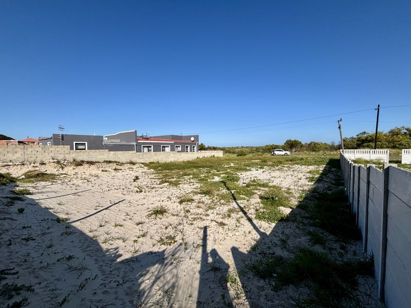 A vacant residential plot featuring sandy ground and enclosed by precast concrete boundary walls.