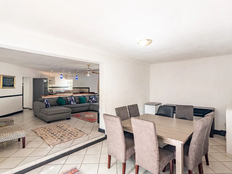 Spacious open-plan living and dining area featuring tiled flooring, a ceiling fan, and a functional kitchen layout with a breakfast bar.