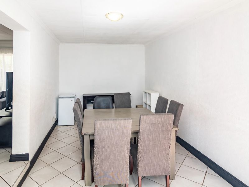 A functional dining area featuring neutral tiled flooring and coved ceilings, providing a blank canvas for modern interior updates.