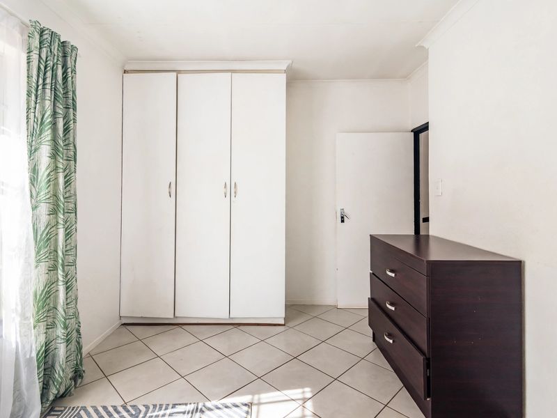 A bedroom featuring tiled flooring and a built-in wardrobe, offering a clean and functional space.