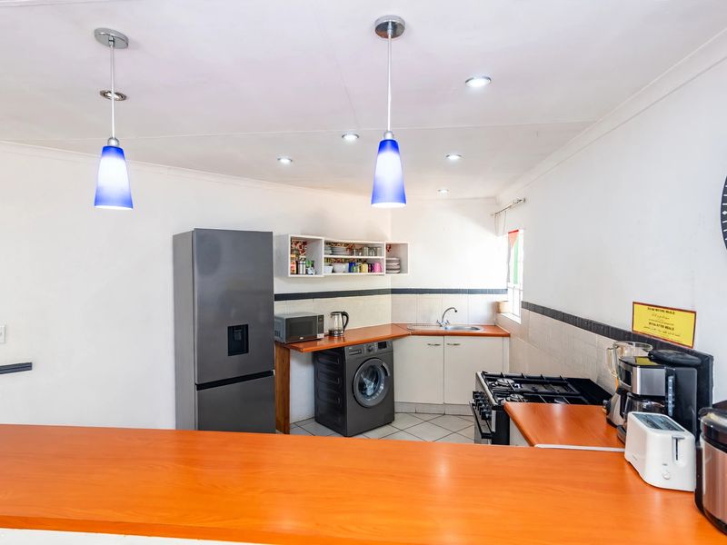 A functional kitchen featuring laminate countertops, built-in cabinetry, a gas stove, and a breakfast bar, illuminated by pendant and recessed lighting.