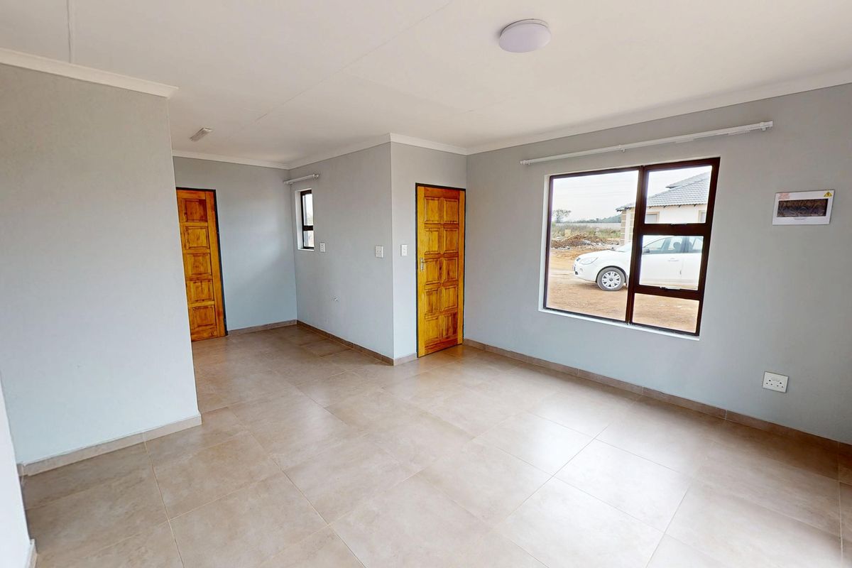 A bright, empty living area featuring neutral wall paint, tiled flooring, and timber doors, offering a clean canvas for interior design.