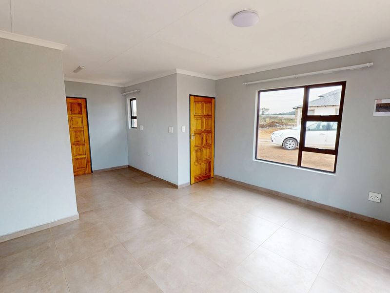 A bright, empty living area featuring neutral wall paint, tiled flooring, and timber doors, offering a clean canvas for interior design.